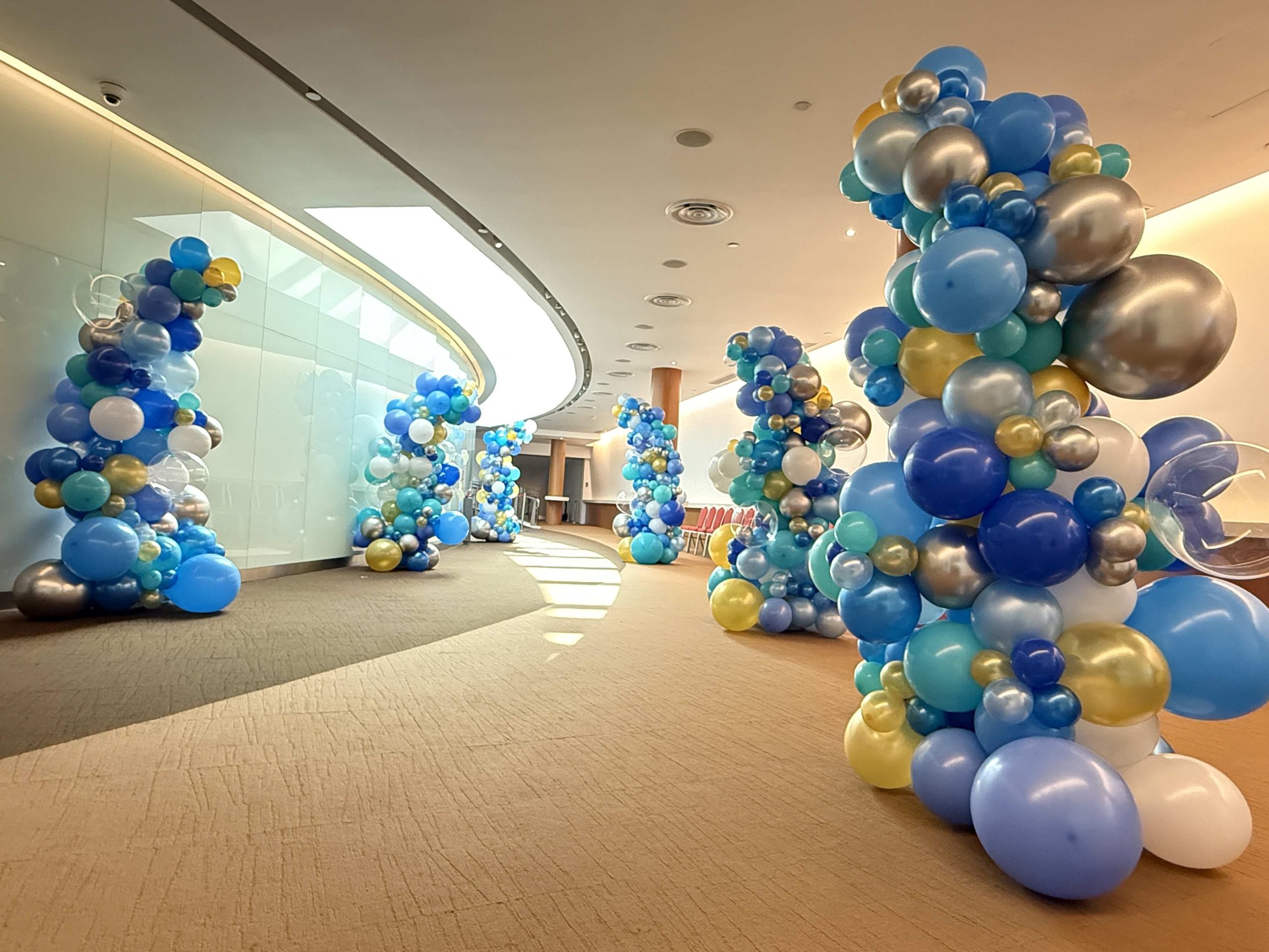 Organic balloon columns in blue and gold for corporate event walkway Singapore