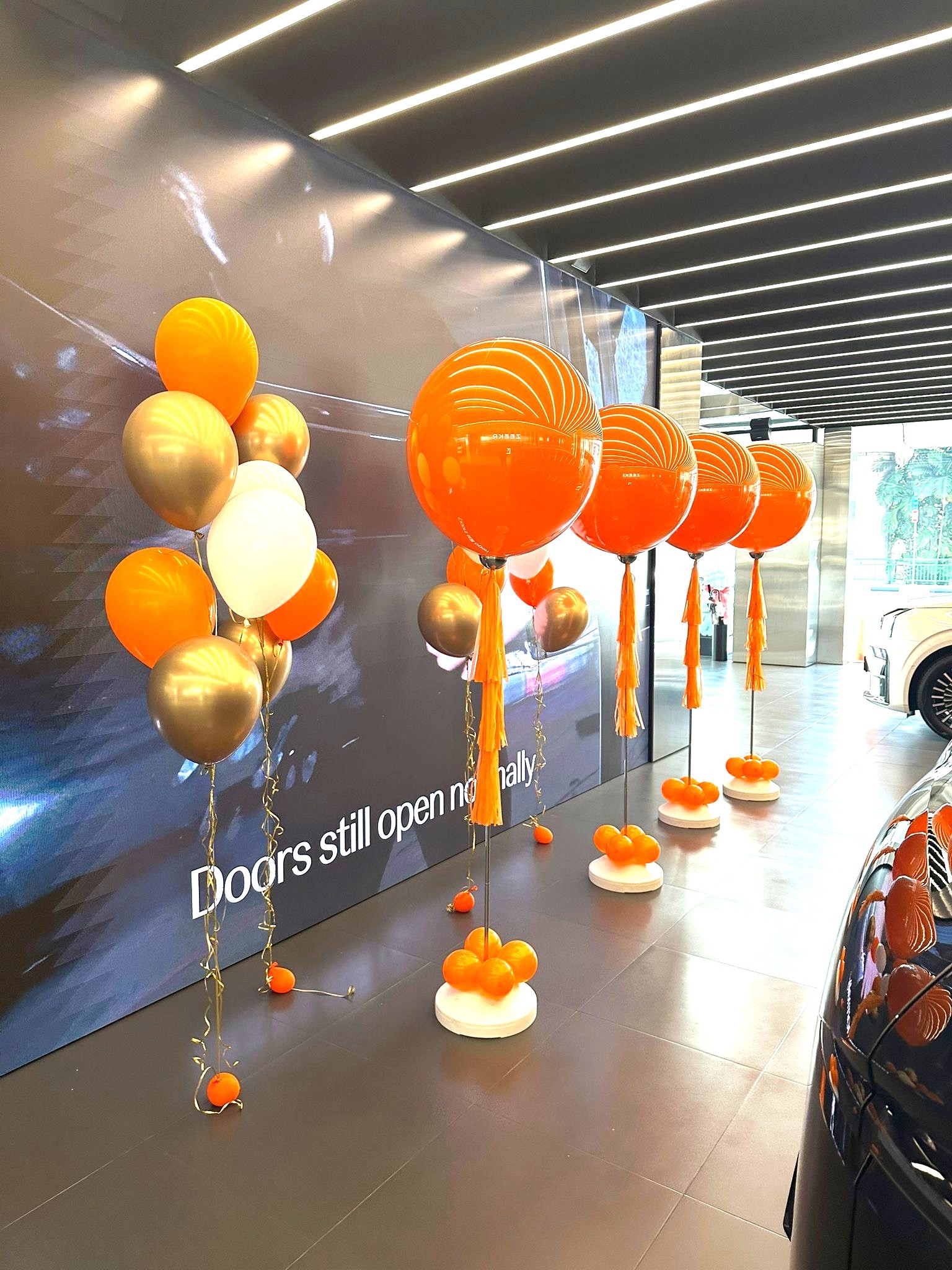 Orange and gold helium balloon stands at a car showroom corporate event in Singapore