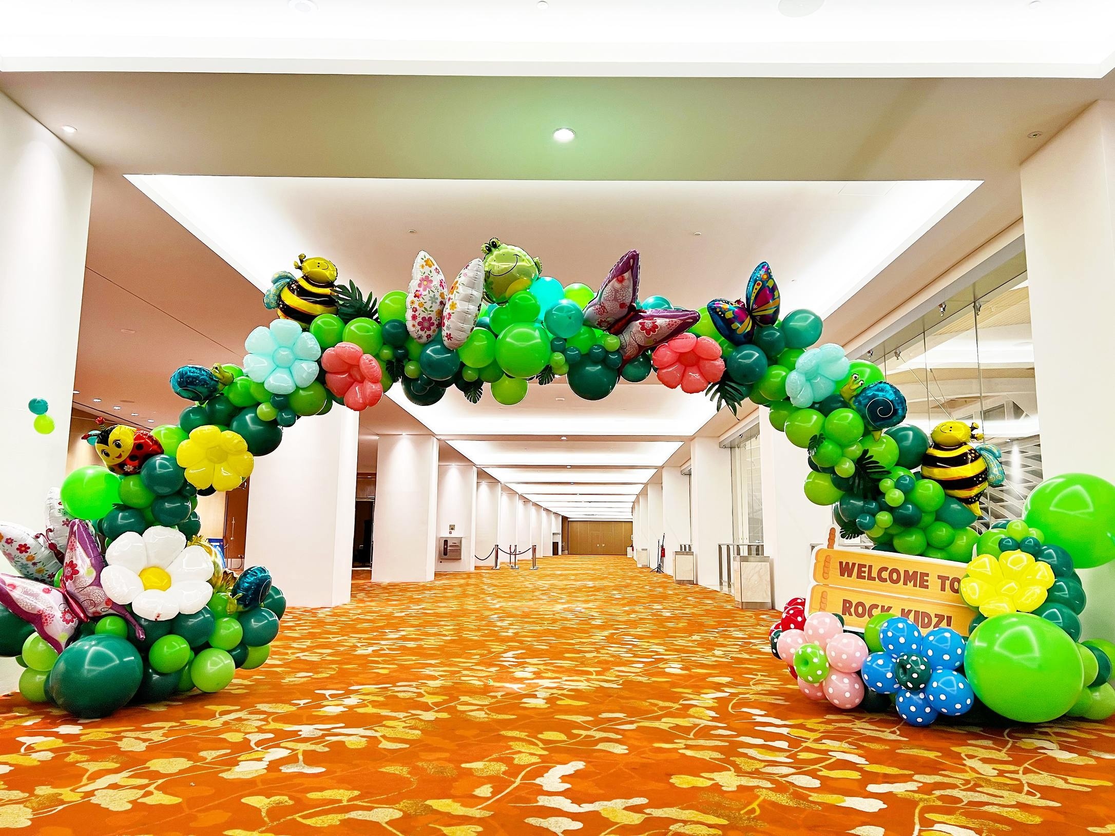 Garden themed balloon arch with insect and flower sculptures