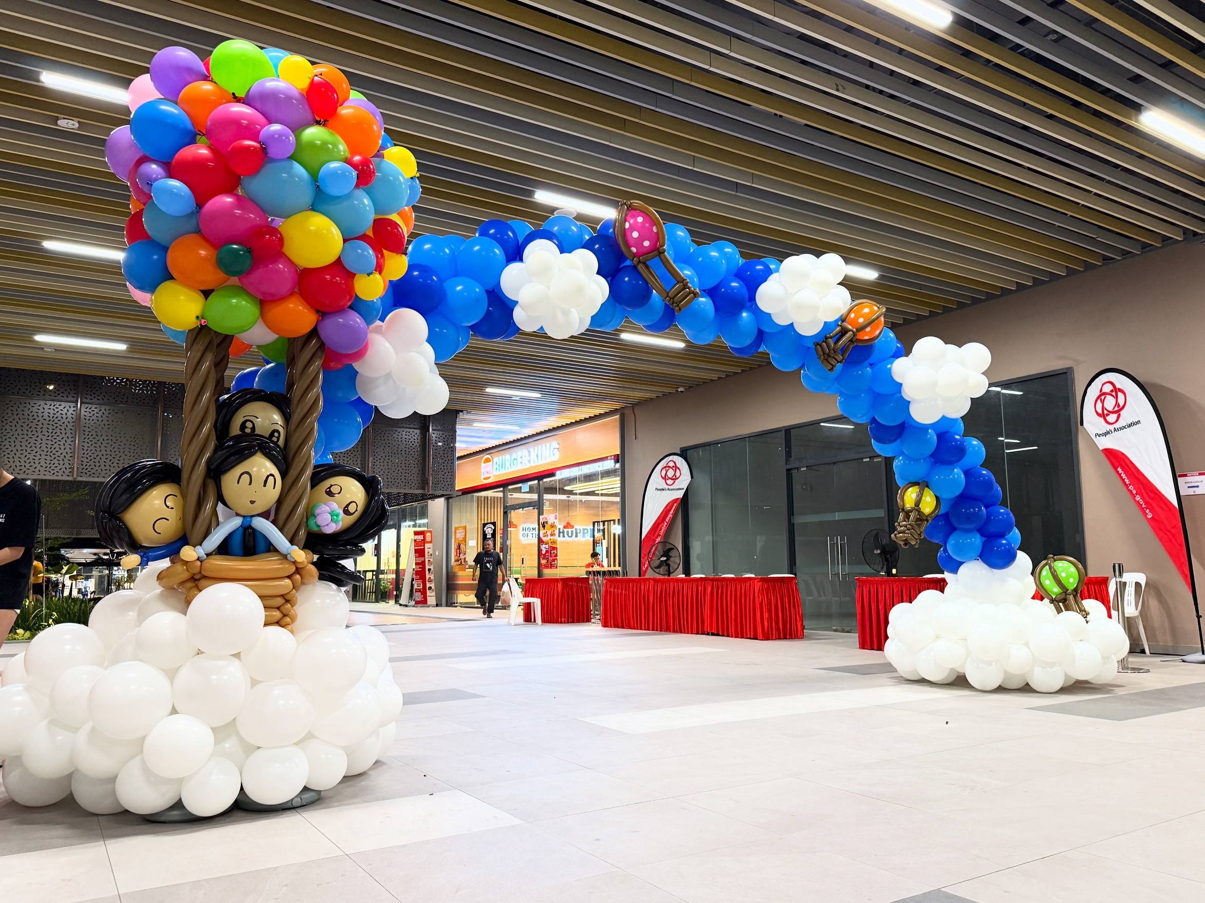 Blue balloon arch with clouds and a hot air balloon sculpture