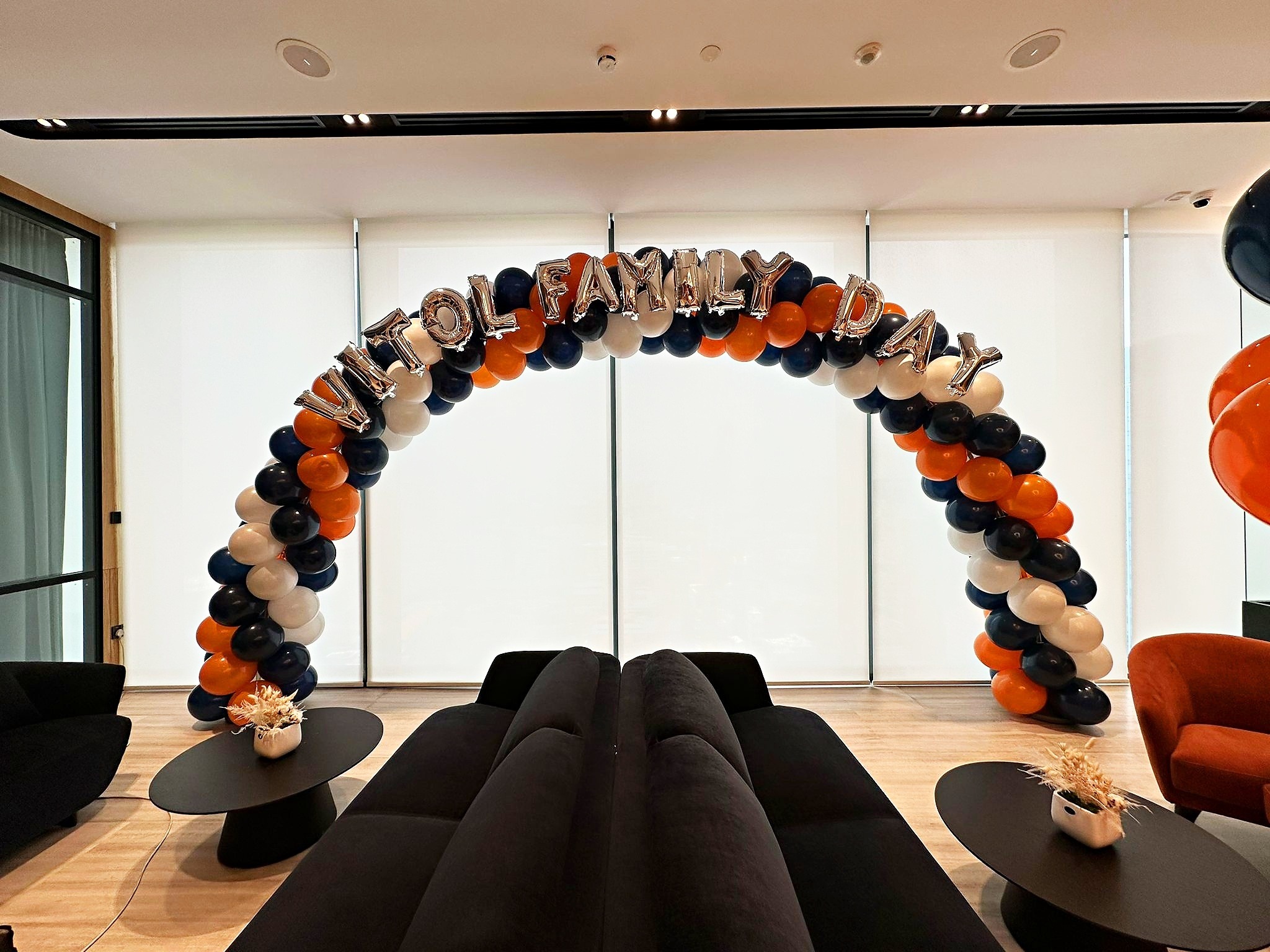Orange black and white balloon arch behind family day lounge seating