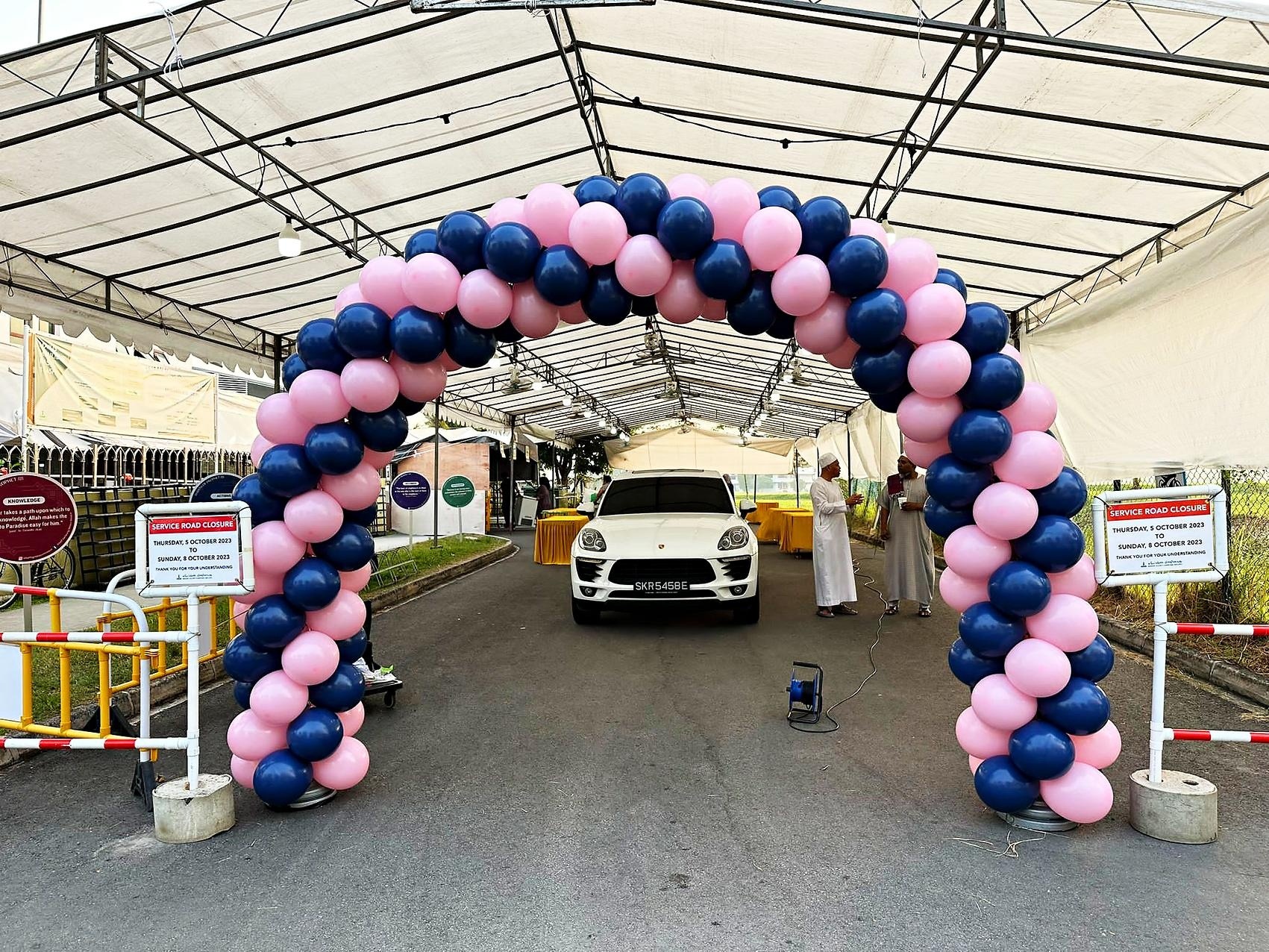 Pink and navy balloon arch framing a vehicle display