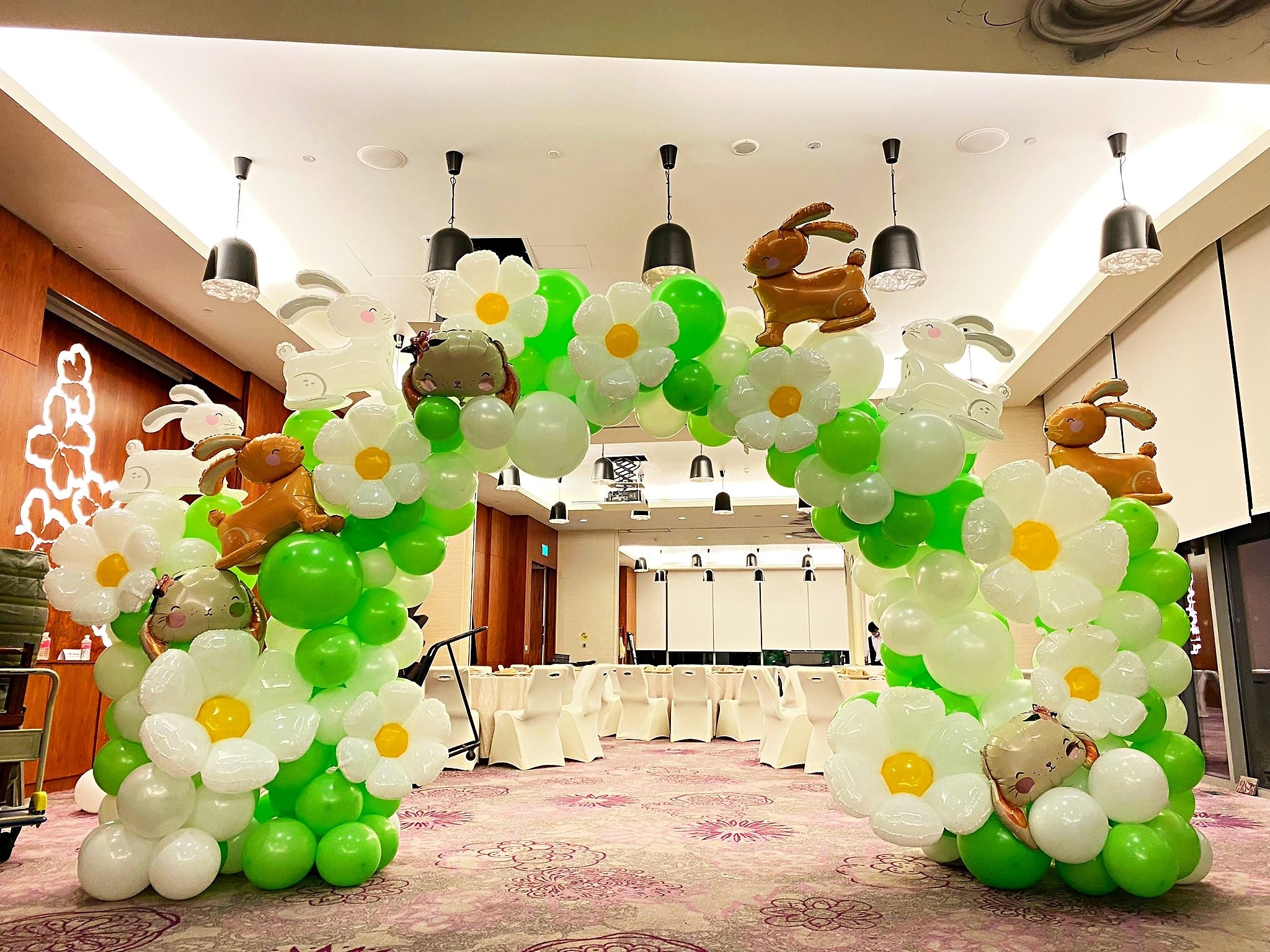 Green and white balloon arch with rabbit and flower details