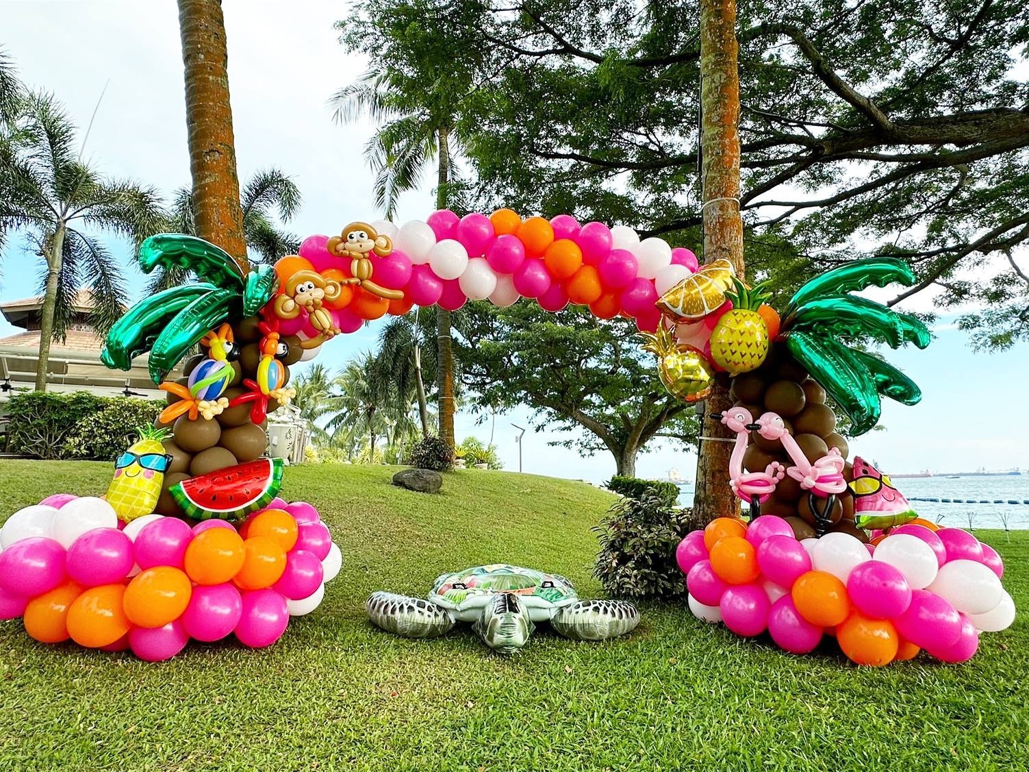 Tropical balloon arch with pink clusters and palm tree details