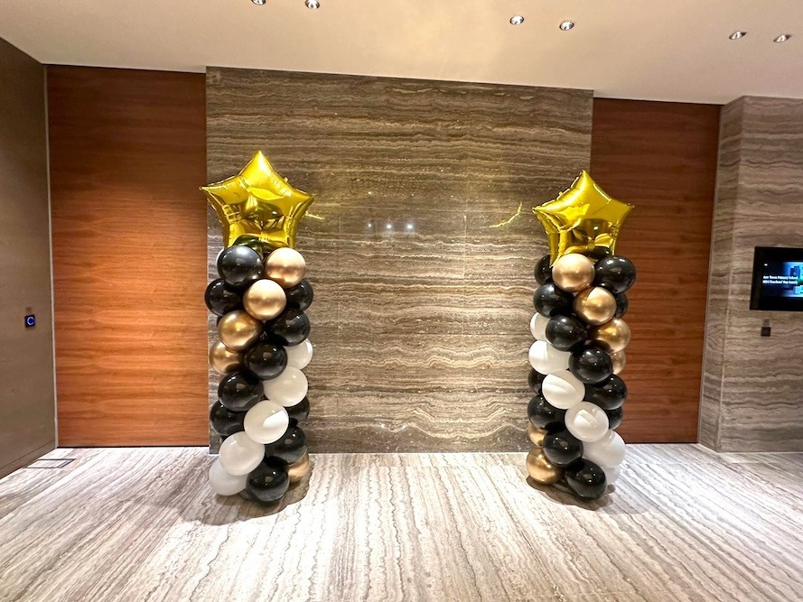 Black gold and white star-topped balloon pillars in a hotel lobby