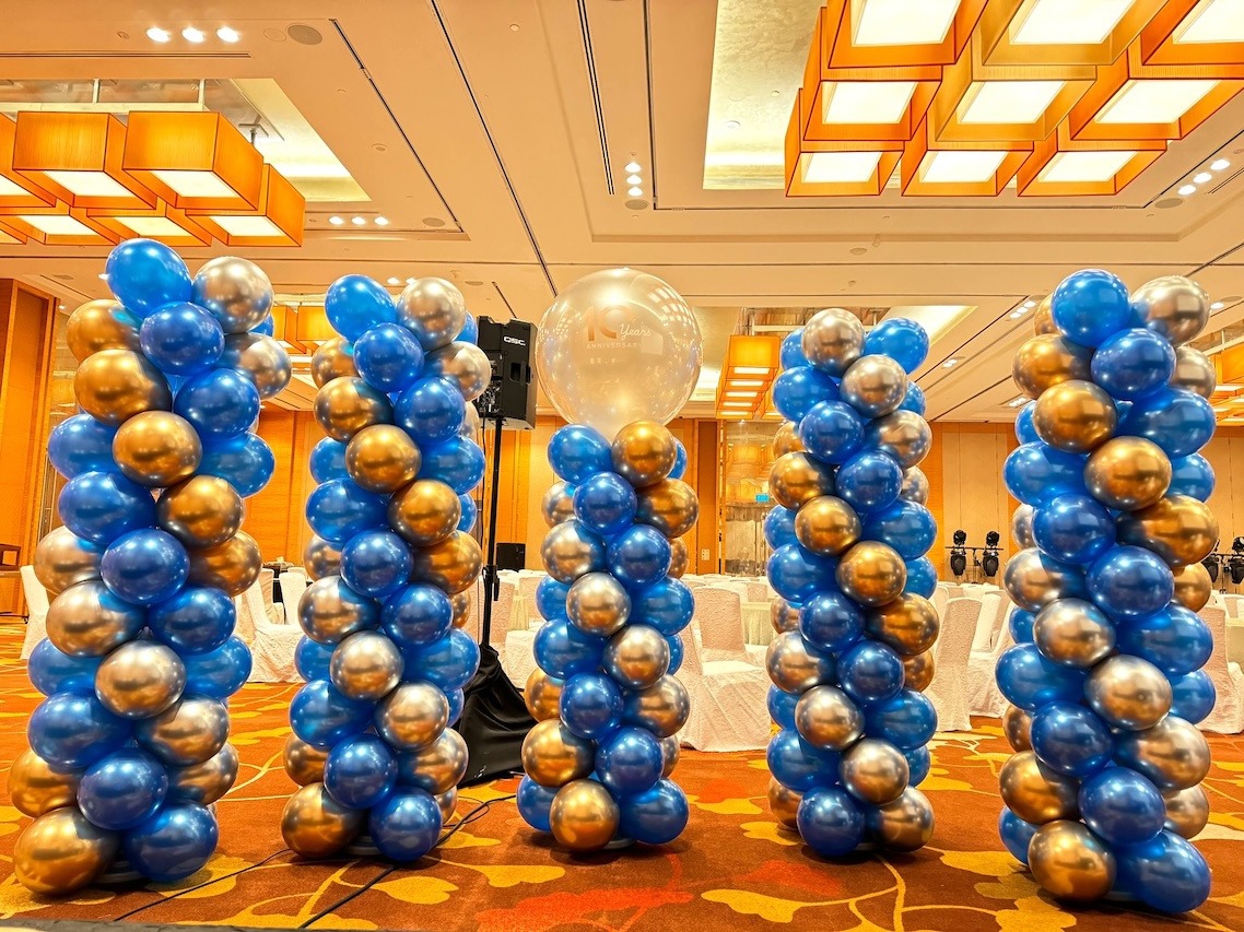 Blue and gold balloon pillars grouped inside a ballroom