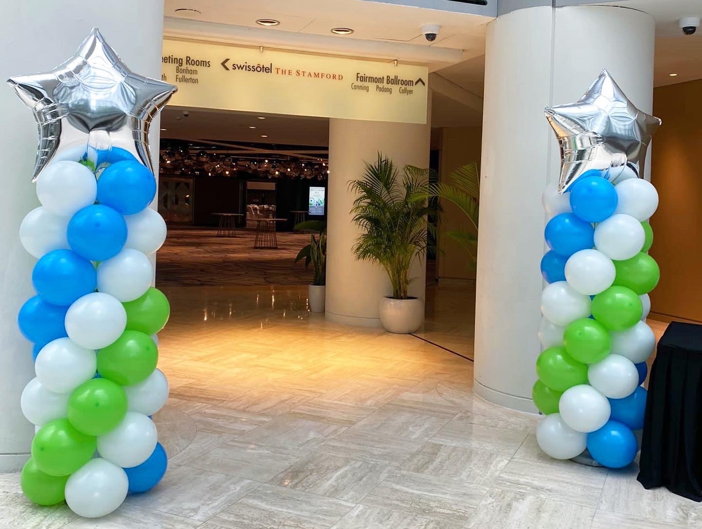 Blue green and white star-topped balloon pillars at a hotel entrance