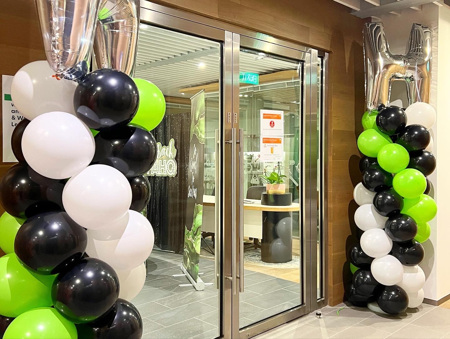 Green black and white balloon columns at a restaurant entrance