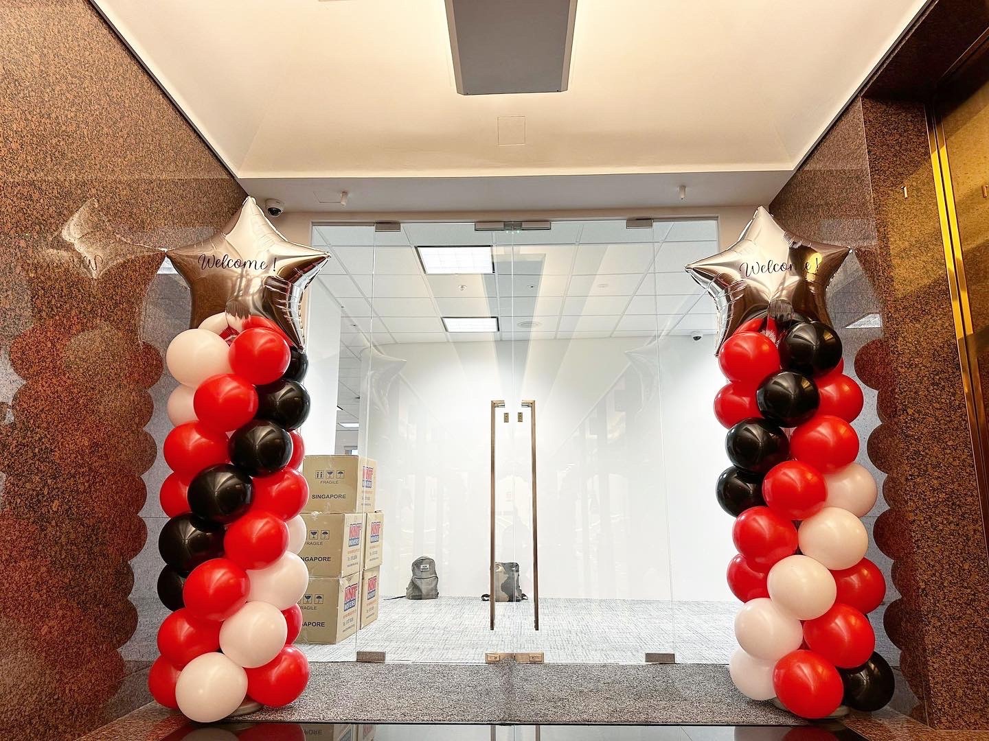 Red black and white balloon pillars beside a glass entrance