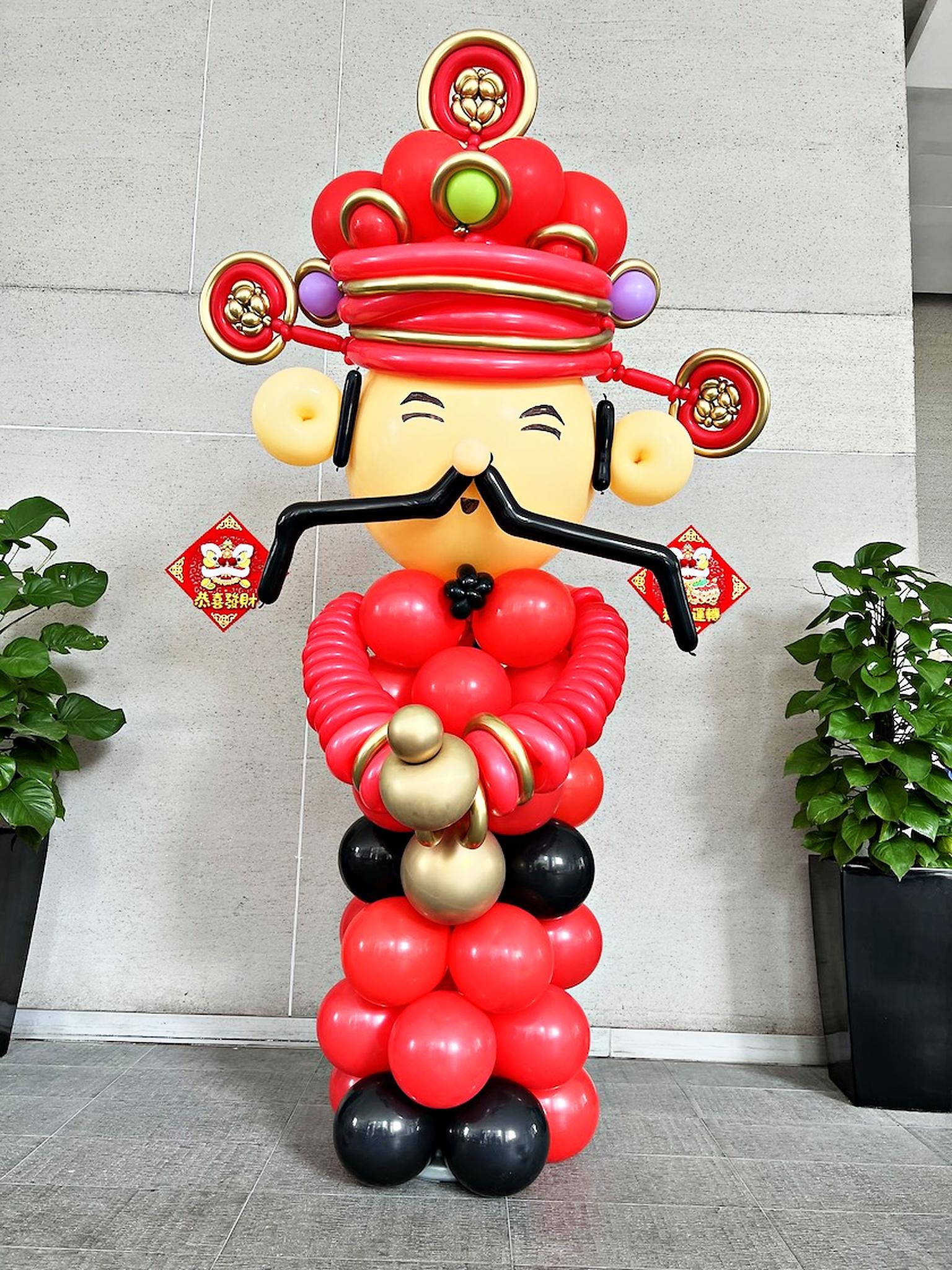 Caishen balloon sculpture displayed against an office wall