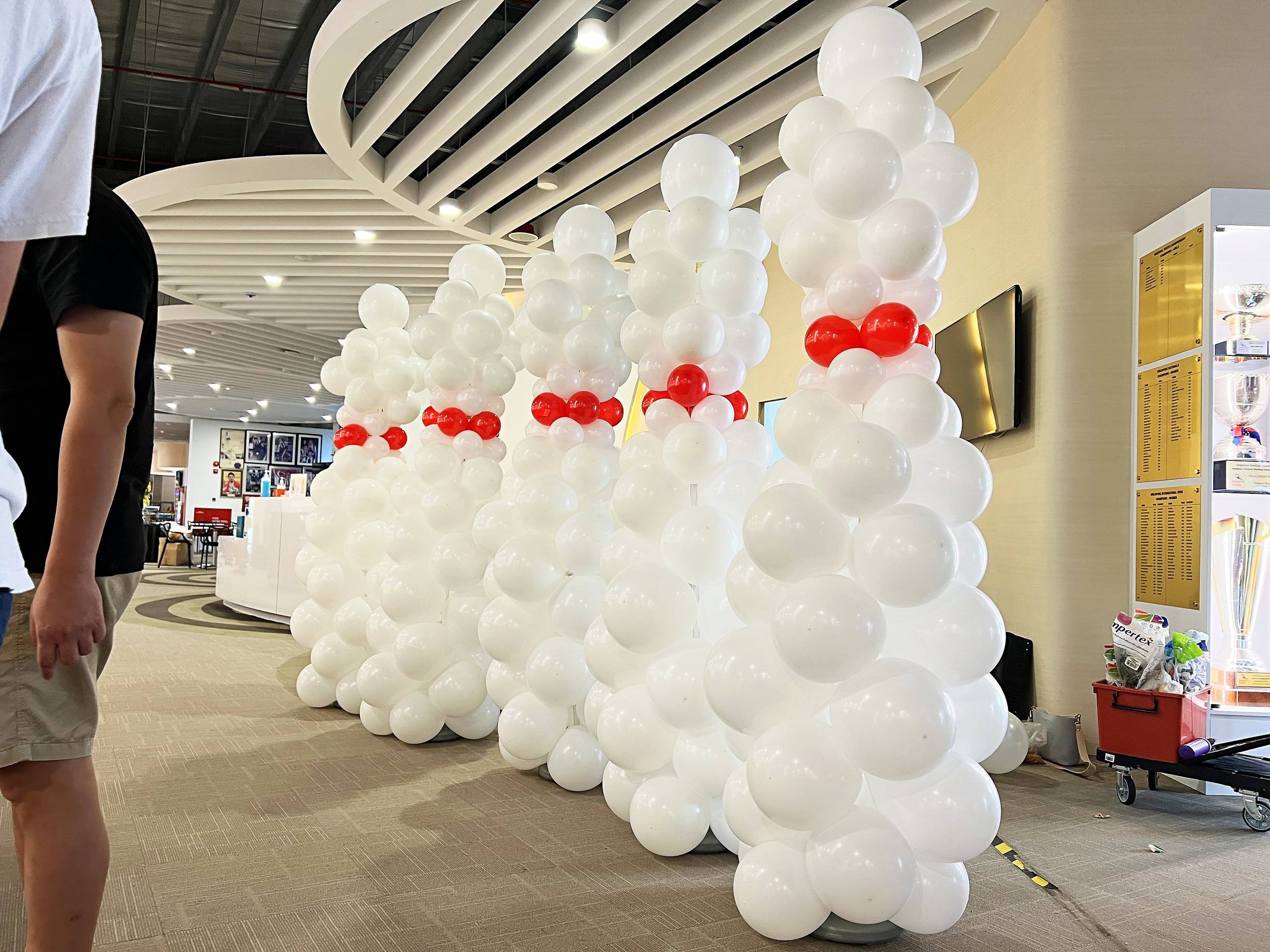 White bowling pin balloon sculptures with red neck bands