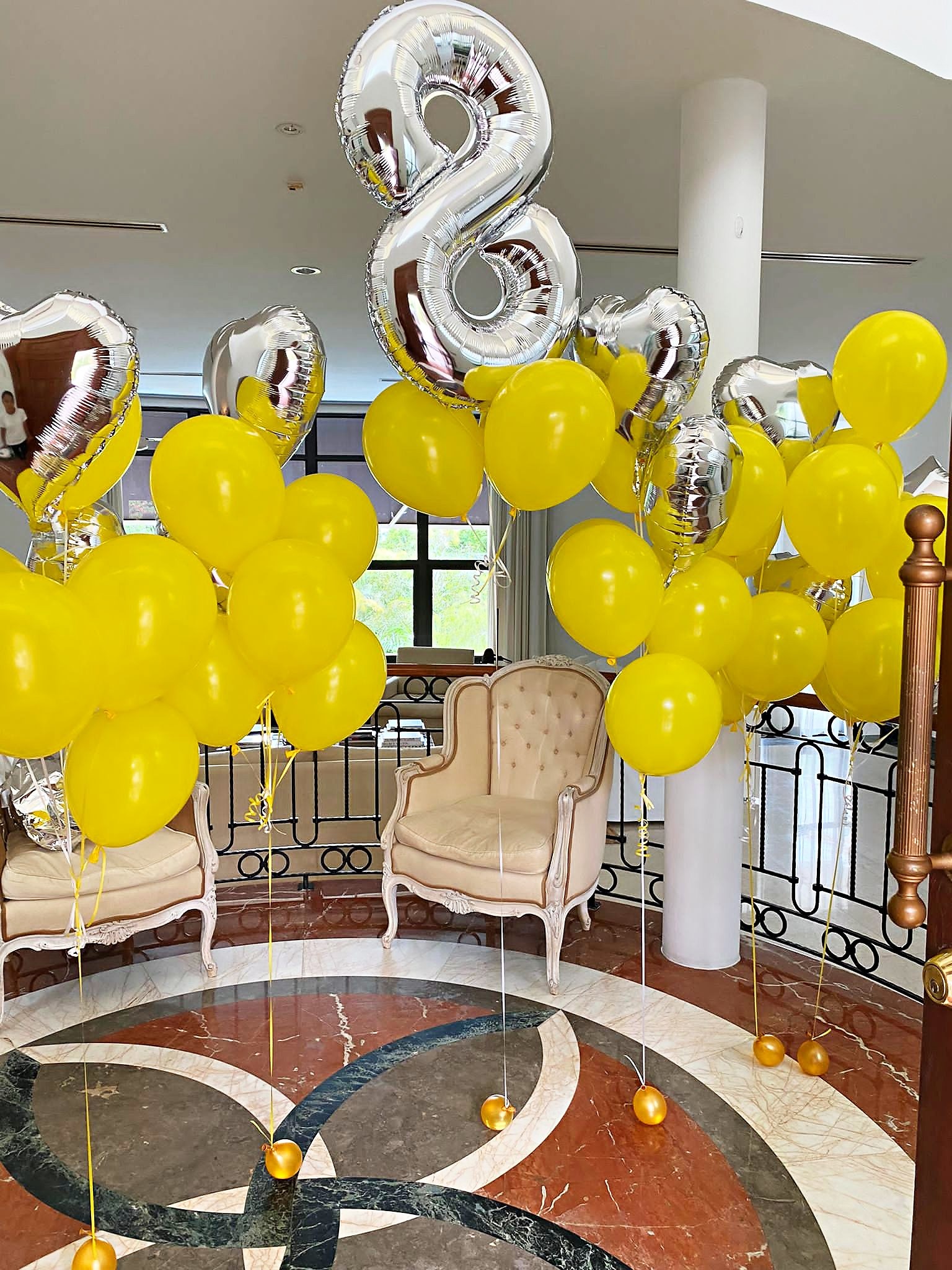 Yellow and silver helium balloon arrangement beside a birthday chair